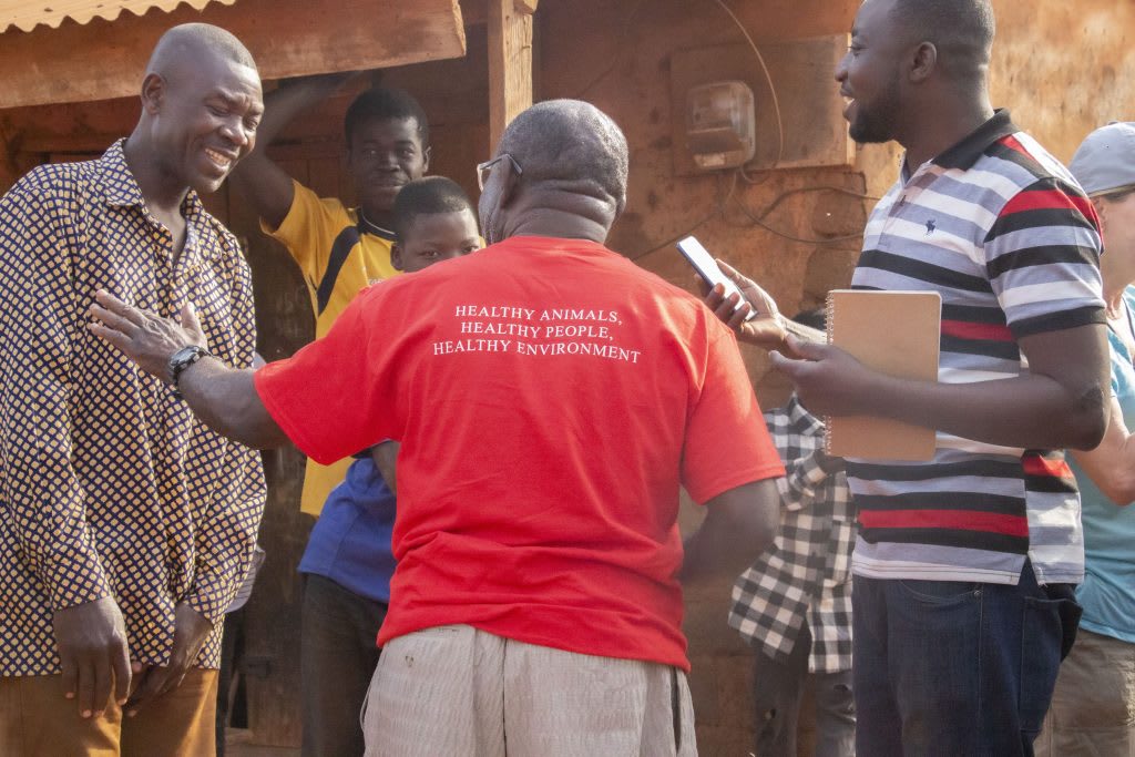 A volunteer talks to a group of men who are laughing.