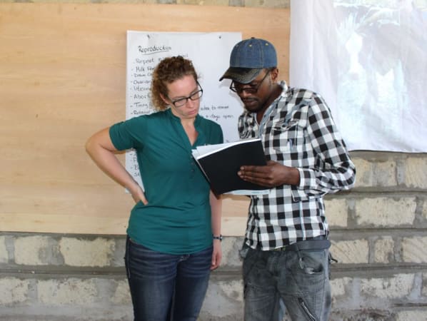A volunteer and a Kenyan dairy cooperative employee look over some paperwork.