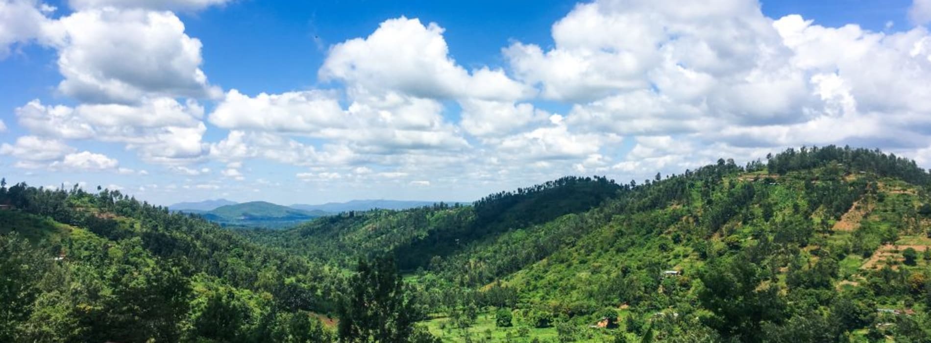 Landscape shot of hilly Kenyan countryside with blue skies and fluffy clouds.