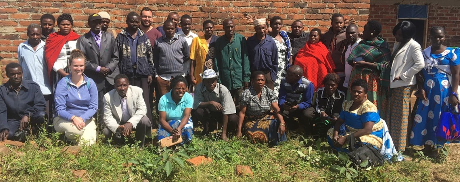 A group of volunteers and local residents standing in front of a brick building.